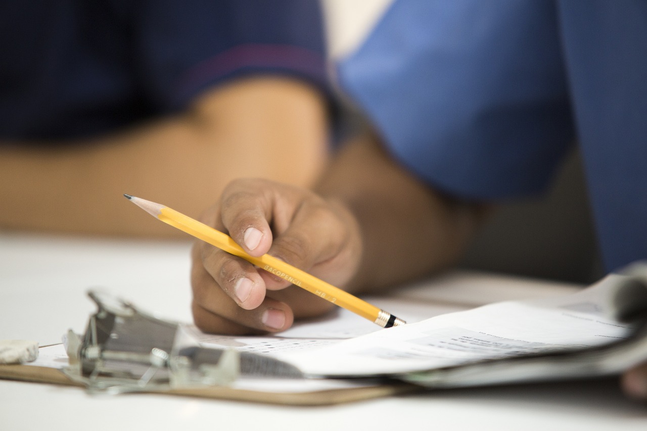 Una mano con un lapiz sobre un cuestionario de examen en papel
